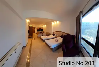 a hotel room with two beds and a large window at Alia Beach Residence in Hurghada