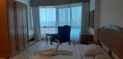 a bedroom with a bed and a chair and a window at Alia Beach Residence in Hurghada