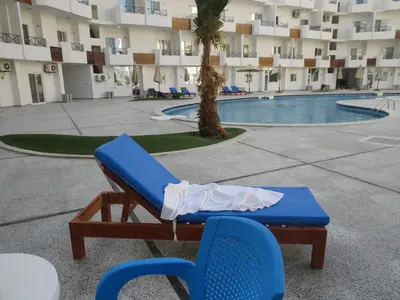 a chaise lounge in front of a building with a pool at Apartment Bella Donna near the sea RedSeaLine. in Hurghada