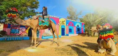 a woman riding on the back of a camel at Nubian Farm Aswan in Aswan
