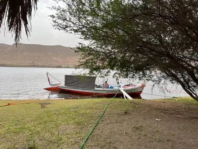 a boat on a lake with a person in it at Felucca Sailing Boat Overnight Experience in Aswan