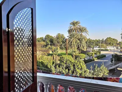 a window with a view of a park from a balcony at Luxor hotel Bella Vista Apartments and Hotel in Luxor