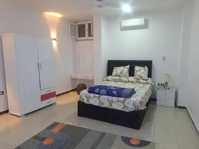 a bedroom with a large bed and a white wall at Sweet Home- ممنوع للمصريين Open 24 Hour in Hurghada
