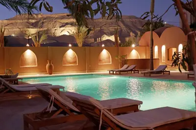 a swimming pool with chaises and chairs in a resort at Malkata House - Boutique hotel and restaurant in Luxor