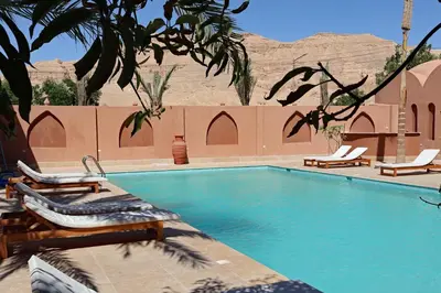 a swimming pool with chaises and chairs next to a building at Malkata House - Boutique hotel and restaurant in Luxor