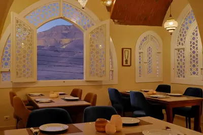 a restaurant with two tables and a large window at Malkata House - Boutique hotel and restaurant in Luxor