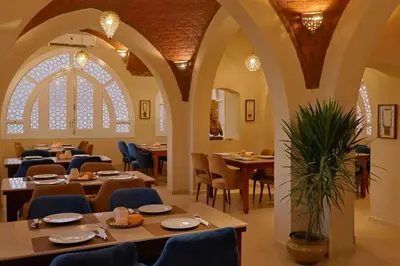 a restaurant with tables and chairs and a large window at Malkata House - Boutique hotel and restaurant in Luxor