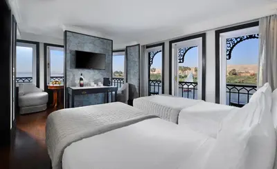 two beds in a hotel room with windows at Movenpick SS Misr Steamer Nile Cruise - 04 & 07 Nights Each Monday From Luxor and 03 Nights Each Friday from Aswan in Luxor