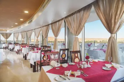 a restaurant with red tables and chairs and windows at Tolip Aswan Hotel in Aswan