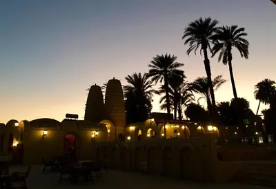 a building with lights and palm trees at sunset at Djorff Palace in Luxor