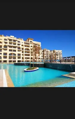 a large building with a palm tree in front of it at Luxury Hurghada Self-Catering Apartments & Studios, Al Dau Heights in Hurghada