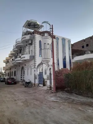 a white building with a car parked in front of it at Alaa Aldin Flats in Luxor