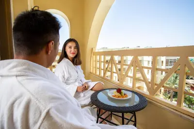 a man and woman sitting on a balcony looking out the window at AMC Royal Hotel & Spa in Hurghada