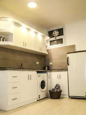 a kitchen with white cabinets and a washer and dryer at Marilyn Studio with Sea View Wi Fi in Hurghada