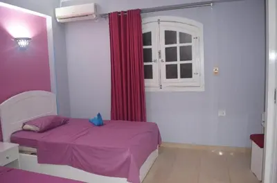 a bedroom with a purple bed and a window at Hermina Guest House in Luxor