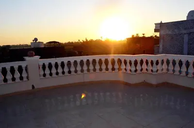 a balcony with a fence and the sunset in the background at Hermina Guest House in Luxor