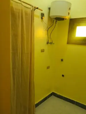 a yellow bathroom with a shower curtain and a window at Roma Guest house in Aswan