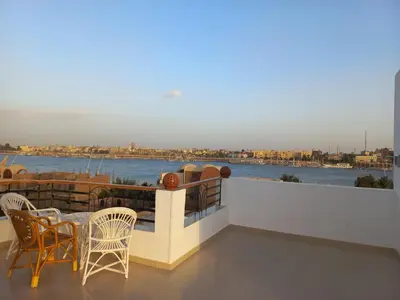 a balcony with a table and chairs and a view of the water at New Modern Flats in Luxor
