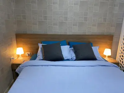 a bedroom with a bed with blue sheets and two lamps at Awesome Pool View Studio in Al Dau Heights in Hurghada