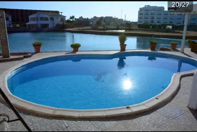 a large blue swimming pool with water in the background at Villa with Private Pool in Hurghada