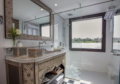 a bathroom with a sink and a mirror and a fireplace at Dahabeya Yakouta Nile Cruise-Every Monday from Luxor- Aswan for 05 nights in Luxor