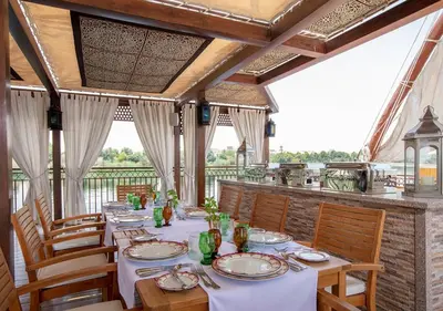a dining room with a table with white tablecloths and chairs at Dahabeya Yakouta Nile Cruise-Every Monday from Luxor- Aswan for 05 nights in Luxor