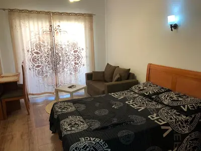 a bedroom with a bed and a couch and a window at Studio Florenza Khamsin in Hurghada