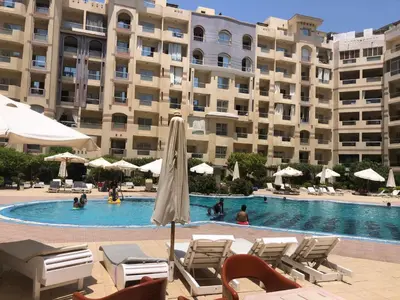 a swimming pool in front of a large building at Studio Florenza Khamsin in Hurghada