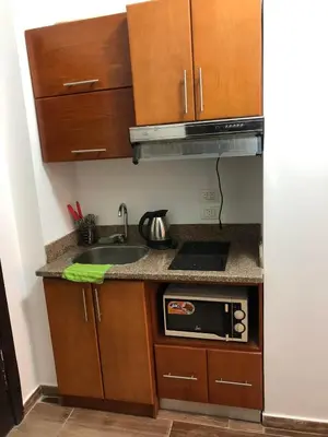a small kitchen with wooden cabinets and a sink at Studio Florenza Khamsin in Hurghada
