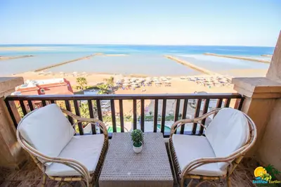 a balcony with two chairs and a view of the beach at BeachView Turtles in Hurghada