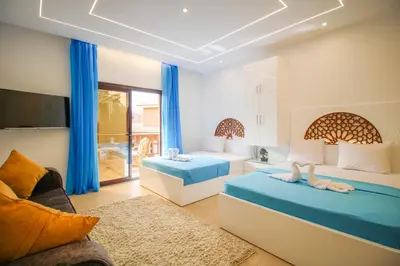two beds in a room with blue curtains at BeachView Turtles in Hurghada