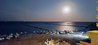 a beach with chairs and umbrellas on the water at night at BeachView Turtles in Hurghada