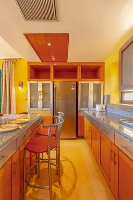 a kitchen with wooden cabinets and a red stool at VESTA - El Gouna Residence in Hurghada