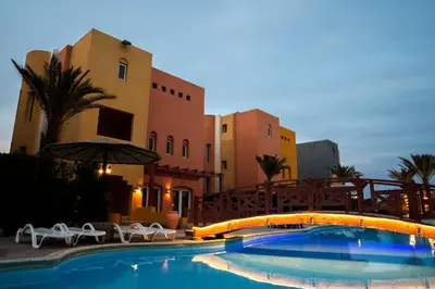 a swimming pool with chairs and an umbrella and buildings at Al Dora Boutique Hotel in Hurghada