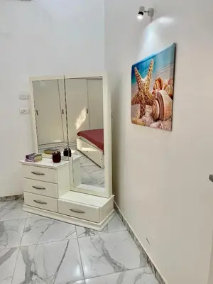 a white bedroom with a mirror and a dresser at Spirit Luxor Luxury in Luxor