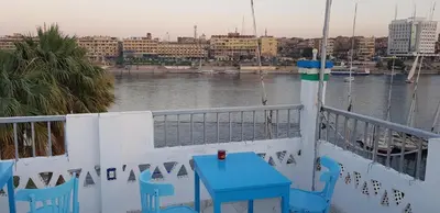 a blue table and chairs on a balcony overlooking a river at Nuba Tod Abouda Guest House in Aswan