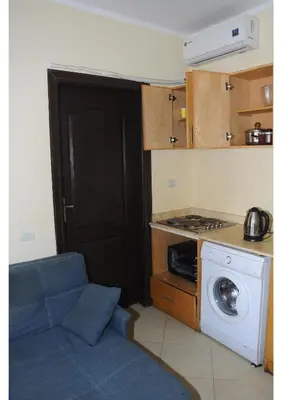 a small kitchen with a washing machine and a blue couch at Apartments in Florenza Khamsin in Hurghada