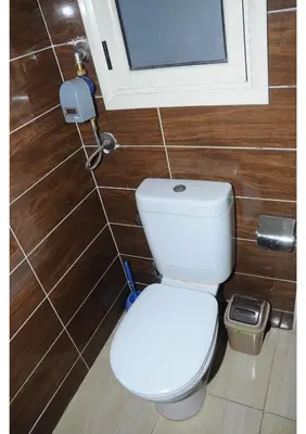 a white toilet in a bathroom with wooden walls at Apartments in Florenza Khamsin in Hurghada
