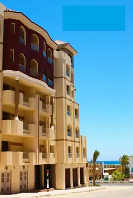 a building next to the beach with the ocean in the background at Apartment I in Florenza Khamsin in Hurghada