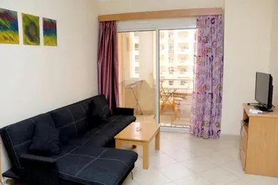 a living room with a black couch and a tv at Apartment F in Florenza Khamsin in Hurghada