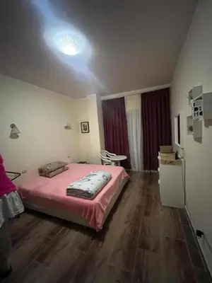 a bedroom with a pink bed and a table in it at Florenza Khamsin 1 bedroom apartment with swimming pool view in Hurghada