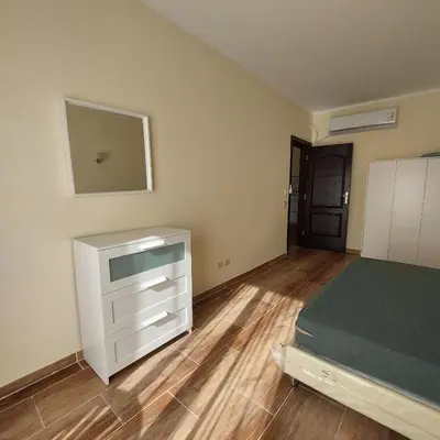 a bedroom with a bed and a dresser and a mirror at Florenza Khamsin 1 bedroom apartment with swimming pool view in Hurghada
