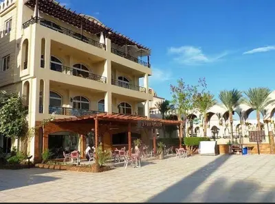 a large building with tables and chairs in a courtyard at Beachfront Cozy One Bedroom apartment Sahl Hasheesh Palma de Piazza in Hurghada