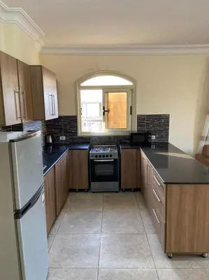 a kitchen with wooden cabinets and a black counter top at Bahga Palace 4 Residential Apartments in Hurghada