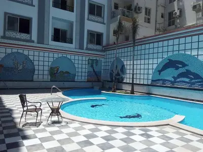 a swimming pool with a table and chairs in a building at apartman Sheraton plaza 419 in Hurghada