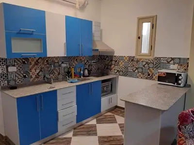 a kitchen with blue cabinets and a tile wall at apartman Sheraton plaza 419 in Hurghada
