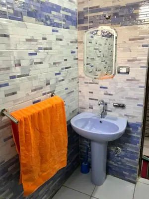 a bathroom with an orange towel next to a sink at NOBATiA Guest House in Aswan