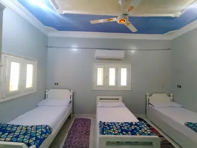 two beds in a room with a ceiling fan at Winji Guest house in Aswan