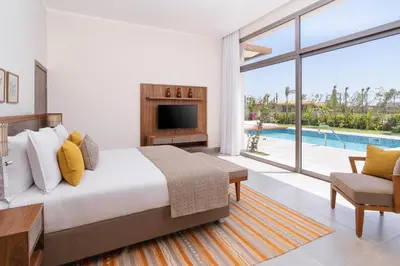 a bedroom with a bed and a tv and a pool at Steigenberger Resort Ras Soma in Hurghada