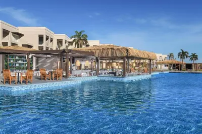a resort with a swimming pool with a thatch roof at Steigenberger Resort Ras Soma in Hurghada